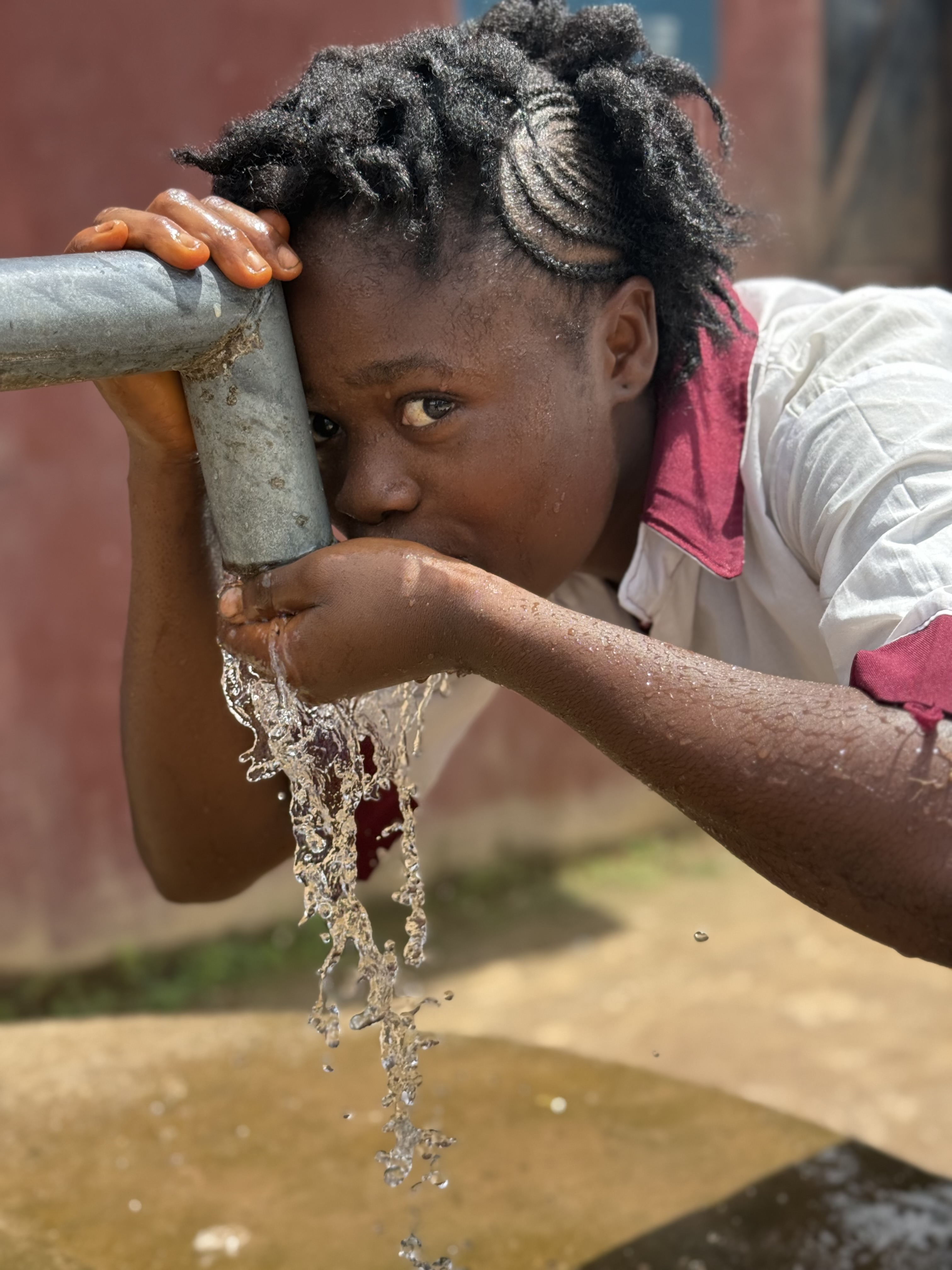 Kind drinkt water uit de waterput in Limba