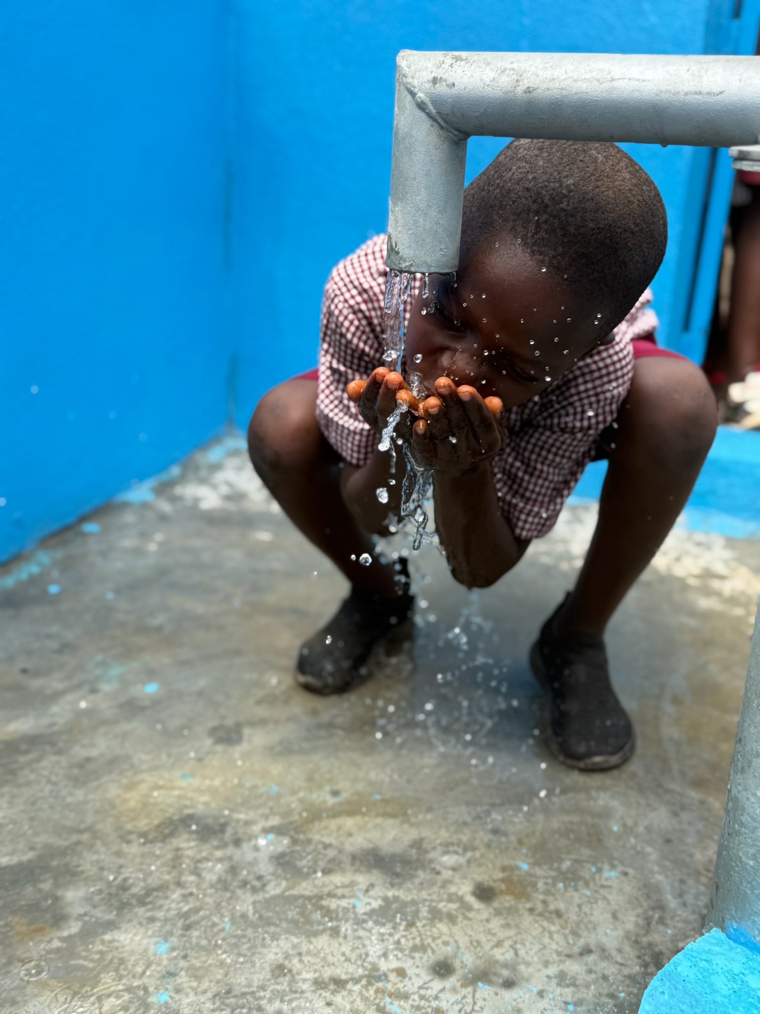 Jongen drinkt water uit een kraan